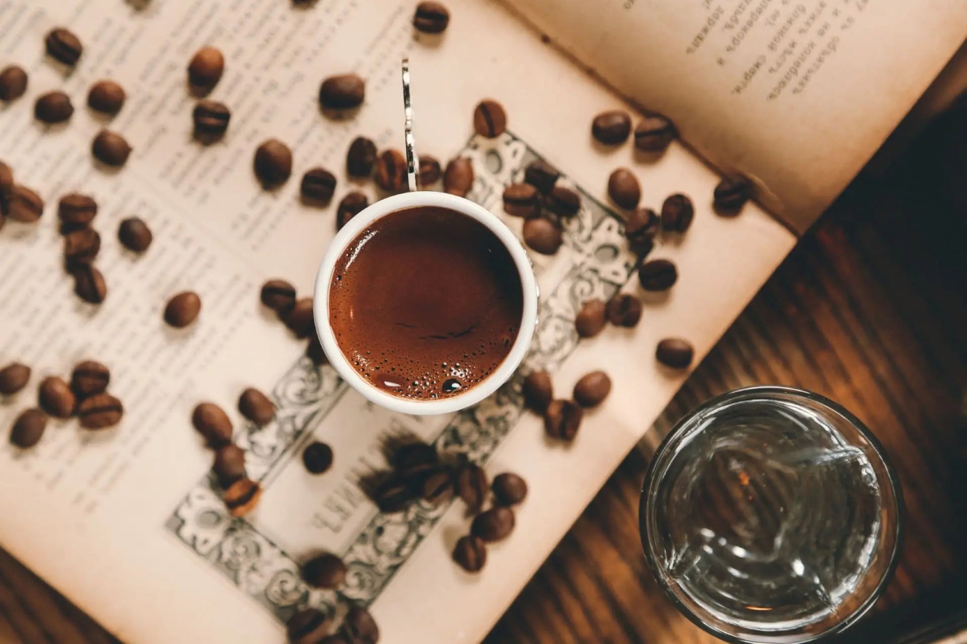 Top view of espresso cup with coffee beans on an open book